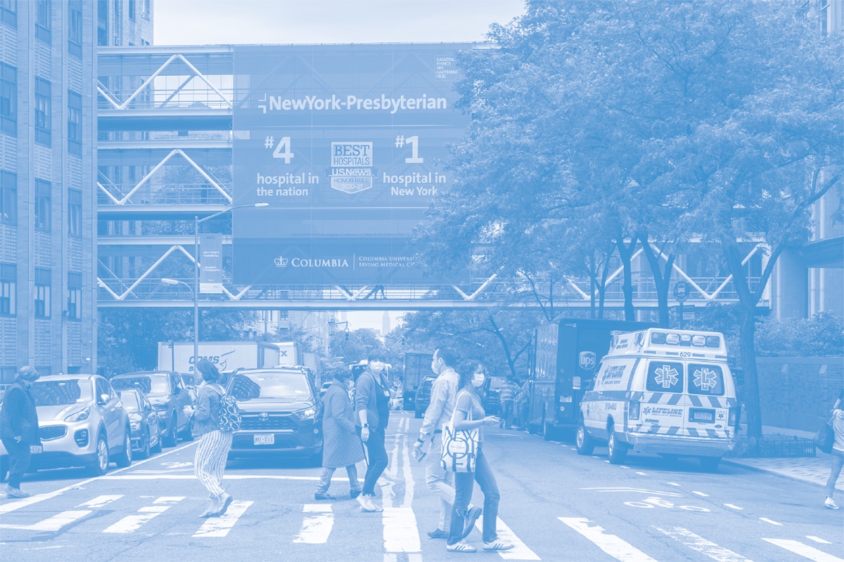 Pedestrians cross the street in front of New York Presbyterian Hospital in an image with a blue color overlay